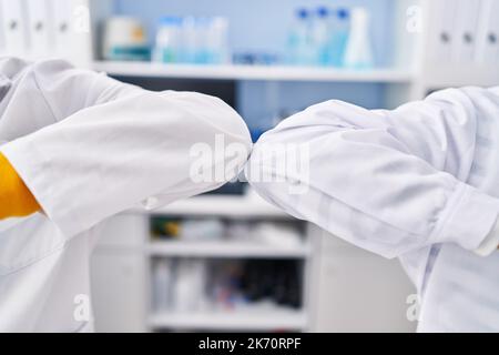 Two man scientists doing elbow greeting at laboratory Stock Photo