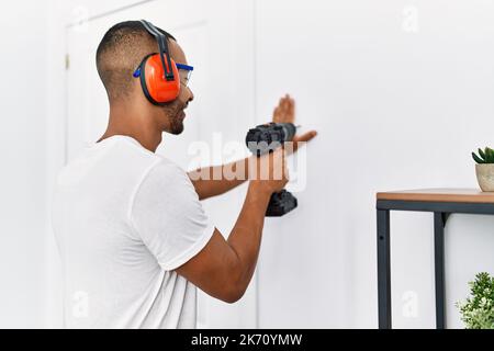 Young hispanic man smiling confident using drill at home Stock Photo