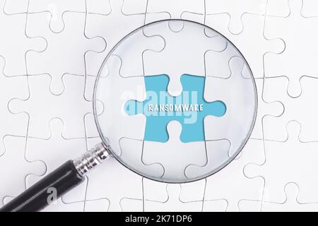 Business Concept - Magnifier Glass on white puzze with RANSOMWARE Word Stock Photo