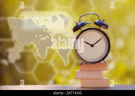 Black alarm clock stacked on wooden bar with shallow DOF green background Stock Photo