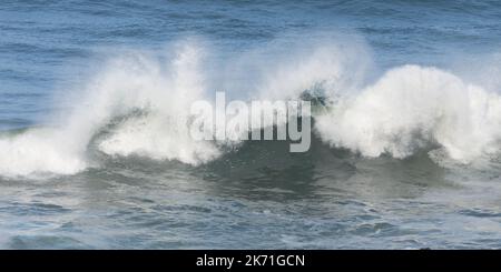 Ocean wave crashing in a state of random confusion against blue water Stock Photo