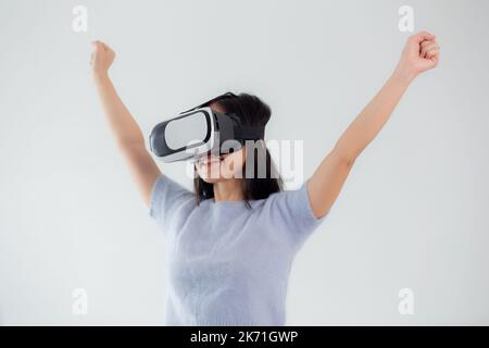 Young asian woman wearing vr headset playing game with excited in the bedroom at home, female using virtual reality or metaverse innovation for simula Stock Photo