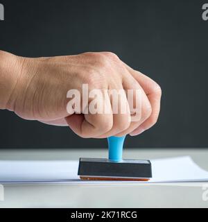 Rubber stamp, hand pressing on paper. Approved or notation concept. Stock Photo