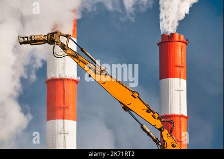 Hydraulic cutter destroys old building against chimneys Stock Photo