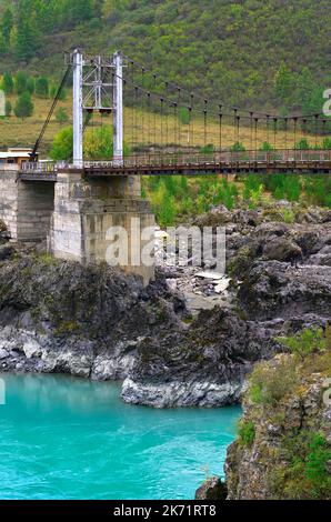 Orokto bridge on the Katuni River. A suspension bridge on the rocky banks of a mountain river with emerald water. Altai Republic, Siberia, Russia, 202 Stock Photo