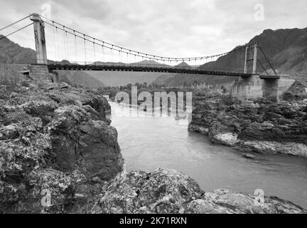 Orokto bridge on the Katuni River. A suspension bridge on the rocky banks of a mountain river. Altai Republic, Siberia, Russia, 2022 Stock Photo