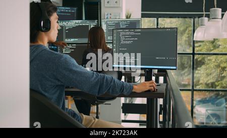 Asian system engineer working with html script on computer screen, using terminal window. Software developer coding system interface, writing innovating ai algorithm in office space. Stock Photo