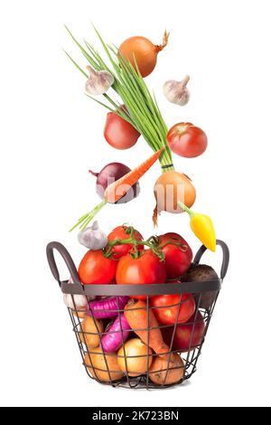 Many healthy vegetables falling into basket on white background Stock Photo