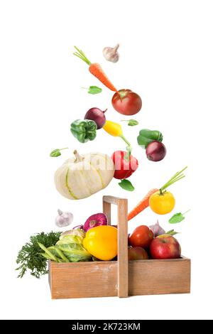 Many healthy vegetables falling into wooden basket on white background Stock Photo