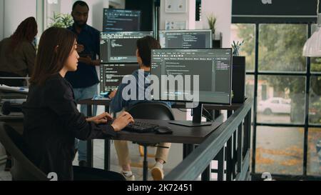 Asian software engineer working with user interface on computer screen to develop new security firewall and html script. Database programer writing code with server algorithms on terminal window. Stock Photo
