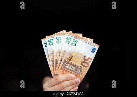 A man holds 100 euro banknotes in his hand on a dark background. cash paper currency, payment, earning and savings, money and finance concept. Empty s Stock Photo