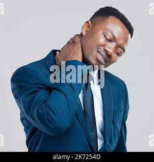 Oh no, not my neck. Studio shot of a young businessman experiencing neck tension against a grey background. Stock Photo