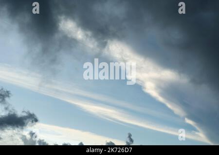 Layers of nimbus and stratus clouds are across the blue of the sky. Stock Photo