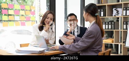 Asian business advisers brainstorms a meeting to analyze and discuss the situation on the financial report in the workspace, Investment Consultant Stock Photo