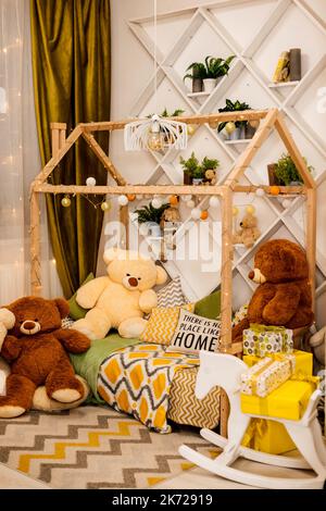 Cozy children's bedroom with bed, garlands, gifts and teddy bears Stock Photo