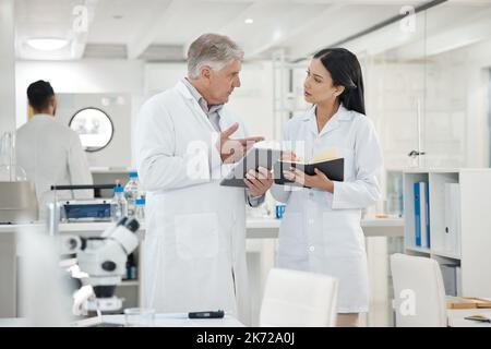 Discussing the new data recorded. two scientists using a digital tablet together in a lab. Stock Photo