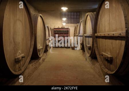 Ancient underground wine cellar with wooden oak casks for wine aging Stock Photo