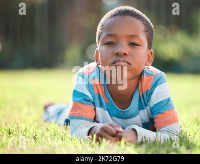 I dont want to go home yet. a young boy lying on the grass outside. Stock Photo