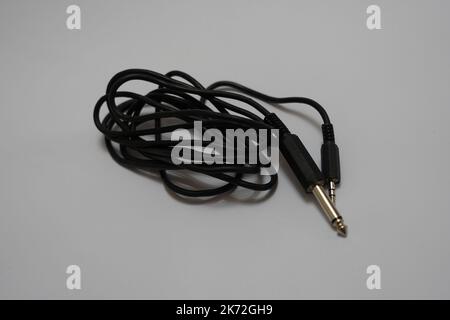Neatly Coiled Black Audio Cable with 3.5mm Jack on Light Background Stock Photo