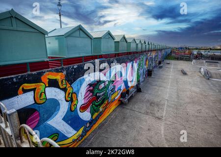 The skate park at The Big Beach Cafe owned by Fat Boy Slim (Norman Cook) on Hove seafront with the beach huts and coilourful street art against a dram Stock Photo