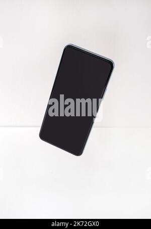 Smartphone mockup, phone with blank screen and shadow flying on white background. Stock Photo