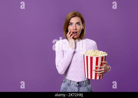 woman watching movie film, holding bucket of popcorn Stock Photo