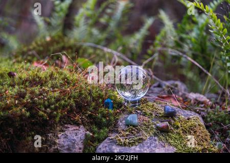 blurred abstract natural green background with stone pyramids and glass ball on moss close up. shallow depth. light art exhibition faucet noise filter Stock Photo