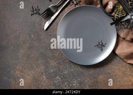 Top view of blank halloween plate on a stone table. Halloween table setting with cutlery. Festive concept. Stock Photo
