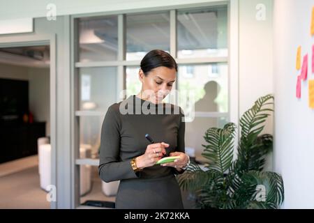 Woman in office making notes on post-its Stock Photo