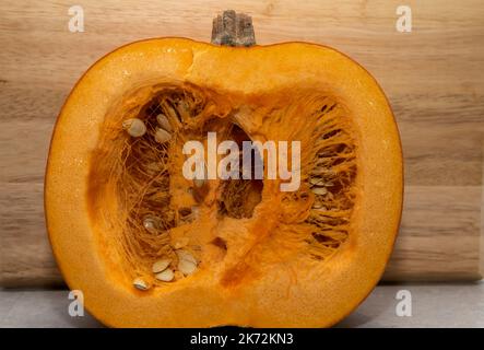 A large Pumpkin cut in half showing the seeds and pulp in the middle Stock Photo