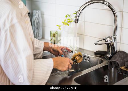 Woman washing dishes in kitchen sink Stock Photo