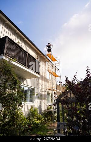 Men on scaffolding renovating house Stock Photo