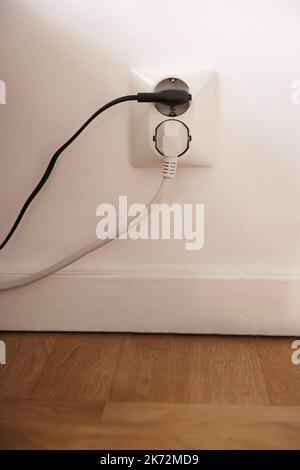 Plugs in wall outlet Stock Photo