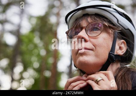 Woman putting on bike helmet Stock Photo