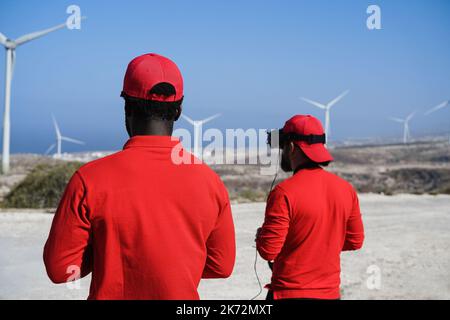 Engineers using virtual reality headset while working at windmill farm - Focus on african man head Stock Photo