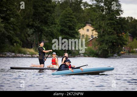 Mother and children paddle boarding on lake Stock Photo