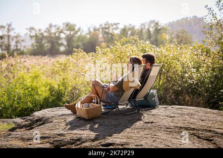 Couple sunbathing on lounge chairs Stock Photo