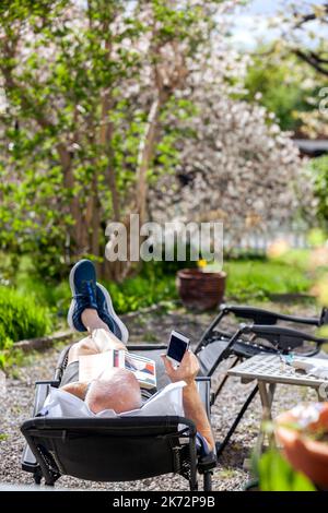 Man relaxing in garden and using smart phone Stock Photo