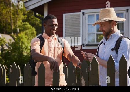 Young men standing near wooden fence Stock Photo