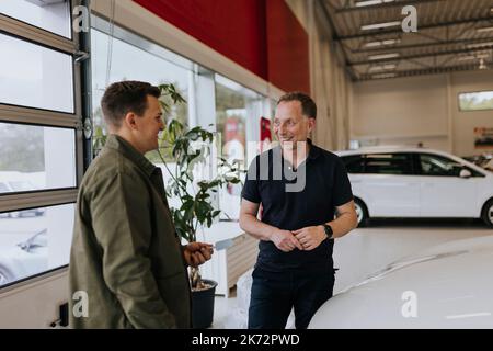Salesman talking to customer in car dealership Stock Photo