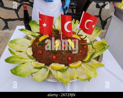 Turkish national food Cig kofte garnished with lettuce, lemon, tomato, hot peppers and Turkish flags. Turkish national food Stock Photo