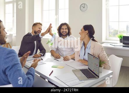 Overjoyed diverse employees give high five celebrate business success Stock Photo