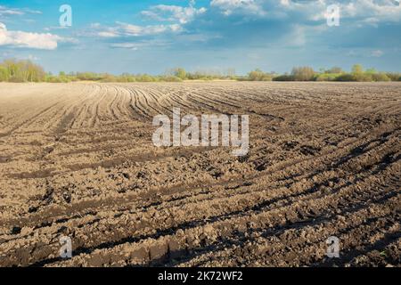 Soil in a plowed farmland, wheel marks on the field Stock Photo