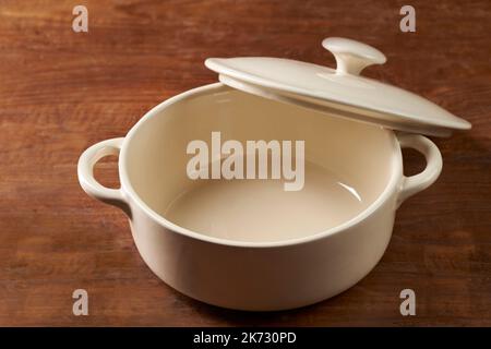 Cooking utensil pot made of ceramic on a wooden table Stock Photo