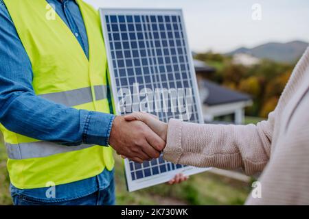Close-up of handyman, photovoltaics panels installer shaking hand with owner of house. Stock Photo