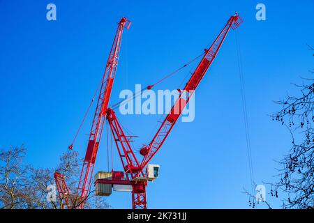 Two tower cranes against a cloudless sky at a construction site in London, England Stock Photo