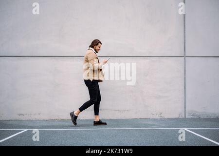 Side view of active businessman feeling busy and chatting messaging at the smartphone while walking Stock Photo