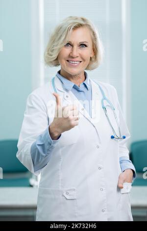 Blonde doctor gives thumb-up gesture in emergency room Stock Photo