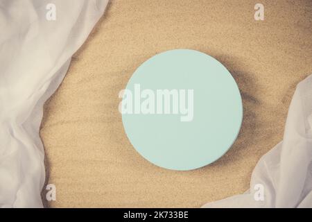 Empty round blue platform podium on white crumpled linen fabric cloth on white natural beach sand background. Minimal creative composition background Stock Photo