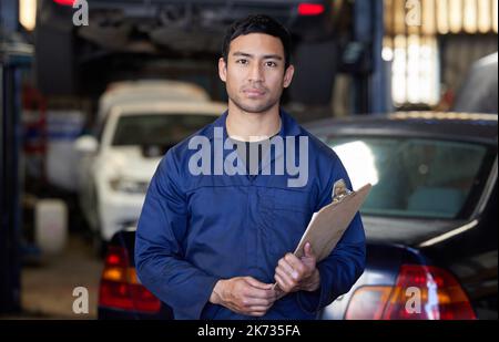 Lets get this inspections underway. Cropped portrait of a handsome young male mechanic holding a clipboard while standing in his workshop. Stock Photo